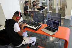 Teen recording keyboard music on a laptop.