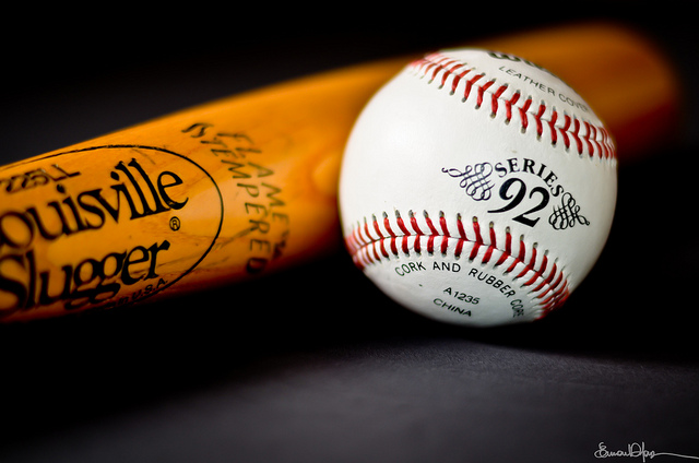 A baseball with a bat behind it.