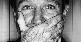 B&W photo of Robin Williams where he is covering his mouth with his hand.