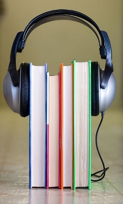 Four books standing on end with headphones stretched over the top.
