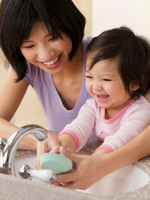 Woman with small child washing hands.