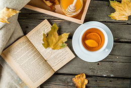 Overhead shot of a picnic table with a cup of tea and an open book.