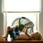 Young boy lays on his back reading a book.