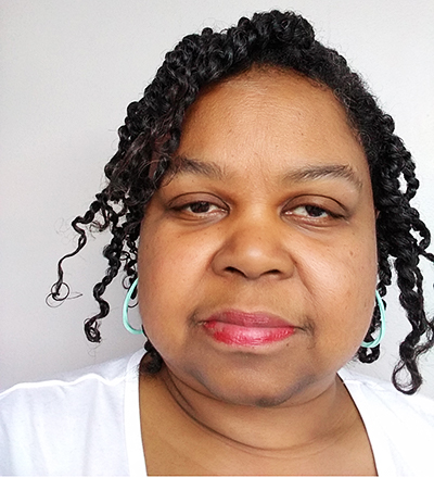 Headshot of a woman with curly black hair.