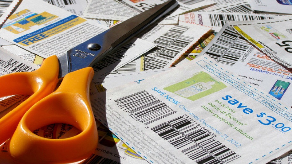 Pile of coupons with orange-handled scissors sitting on top.