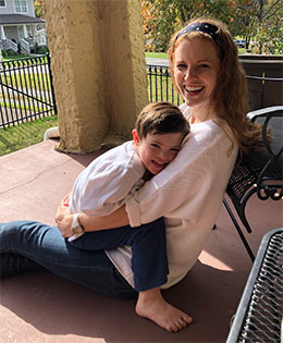 A woman and little boy cuddling on a porch.
