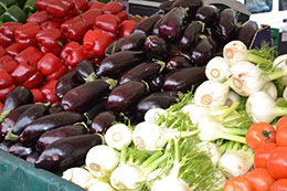 Rows of vegetables like tomatoes, olives, bok choy, and carrots, lined up.