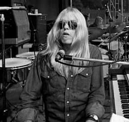 Black and white photo of Gregg Allman playing the organ on stage in front of a massive outdoor festival crowd.