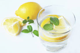 Glass of ice water with mint leaves and lemon slices.