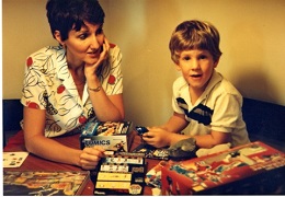 A woman and a young boy smiling while sitting at a table with games.