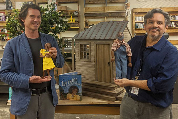 Two men hold marionettes.