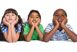 Row of kids laying on their stomachs with their heads in their hands like they're bored.