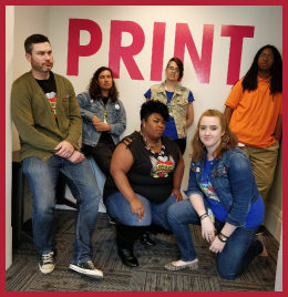Six people pose disinterestedly in front of a wall that reads PRINT.