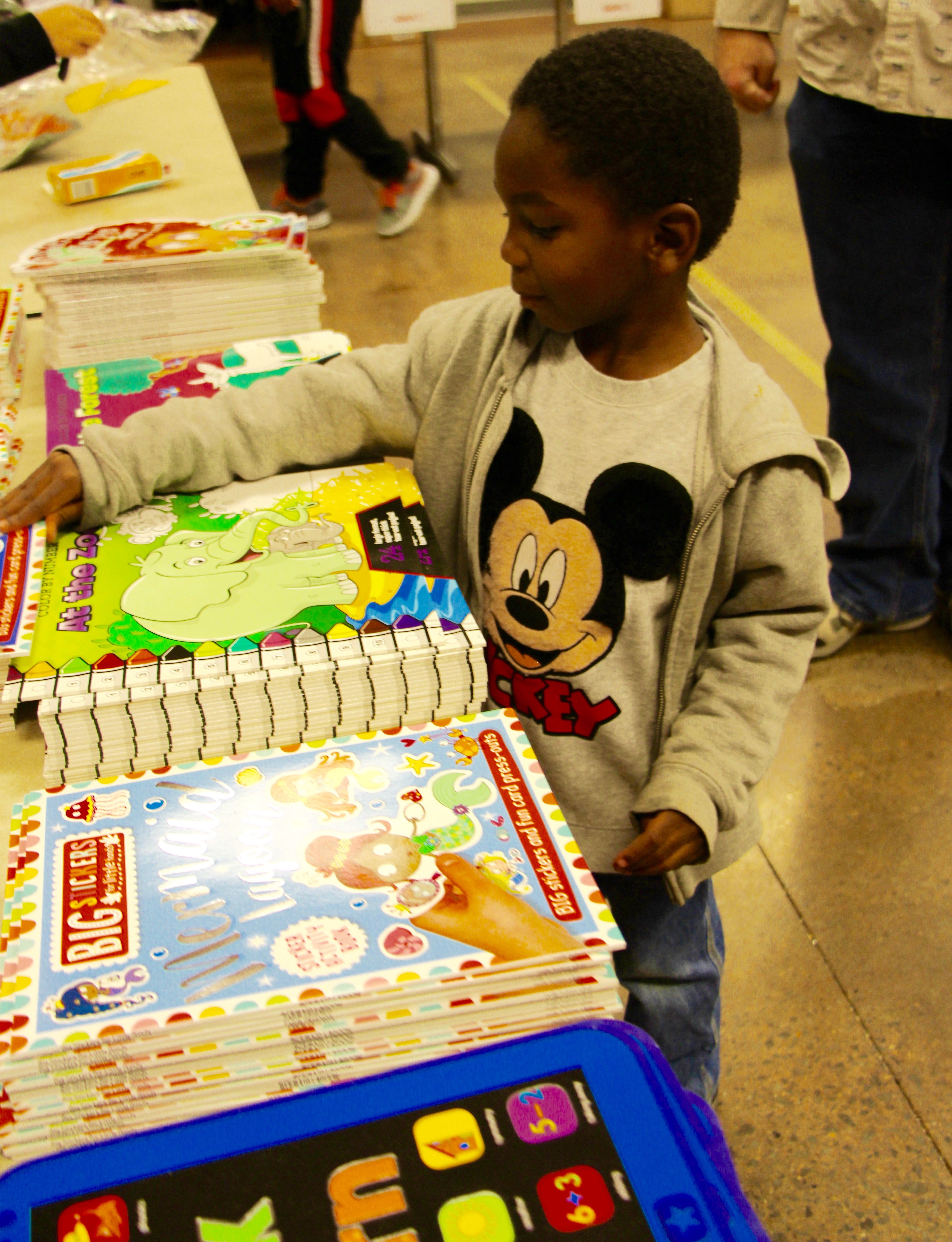 Boy looks at childrens books on a table.
