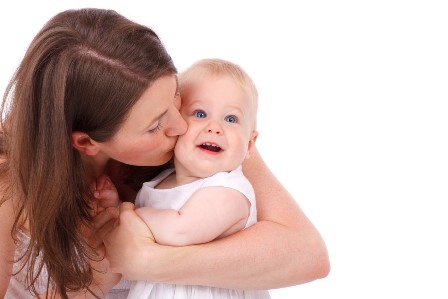 mother kissing smiling baby