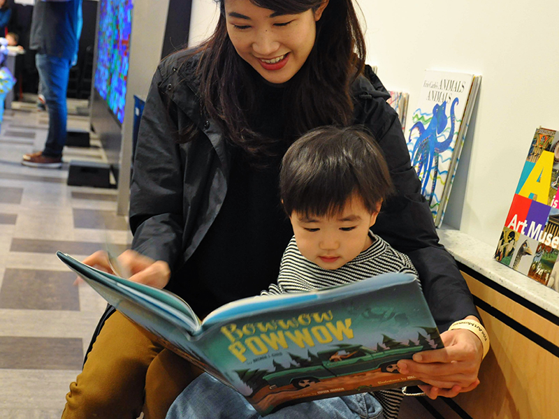 Woman in a black leather jacket reads to a small boy.