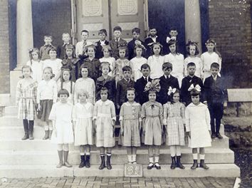 Children pose in three rows on a staircase.