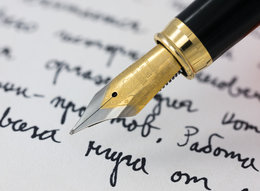 An old fashioned fountain pen hovers of a page with cursive writing.
