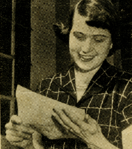 Black and white photo of a woman holding a piece of paper. 