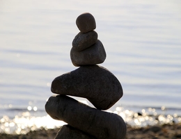 Silhouette of a person doing Tai Chi while standing on a rock near the shore.