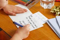 Small hands writing a thank you card.