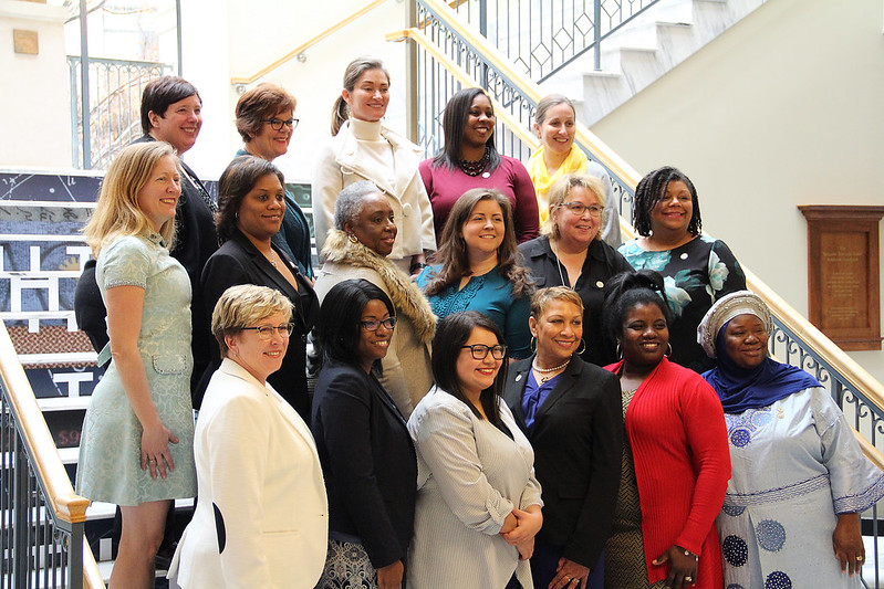 Smiling diverse group of women posing for a photo on wide staircase.
