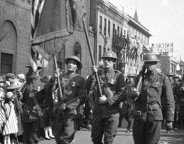 Black and white image of three soldiers marching in World War One parade.