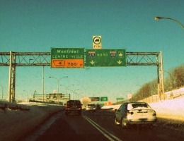 Highway view at sunset with green road sign.