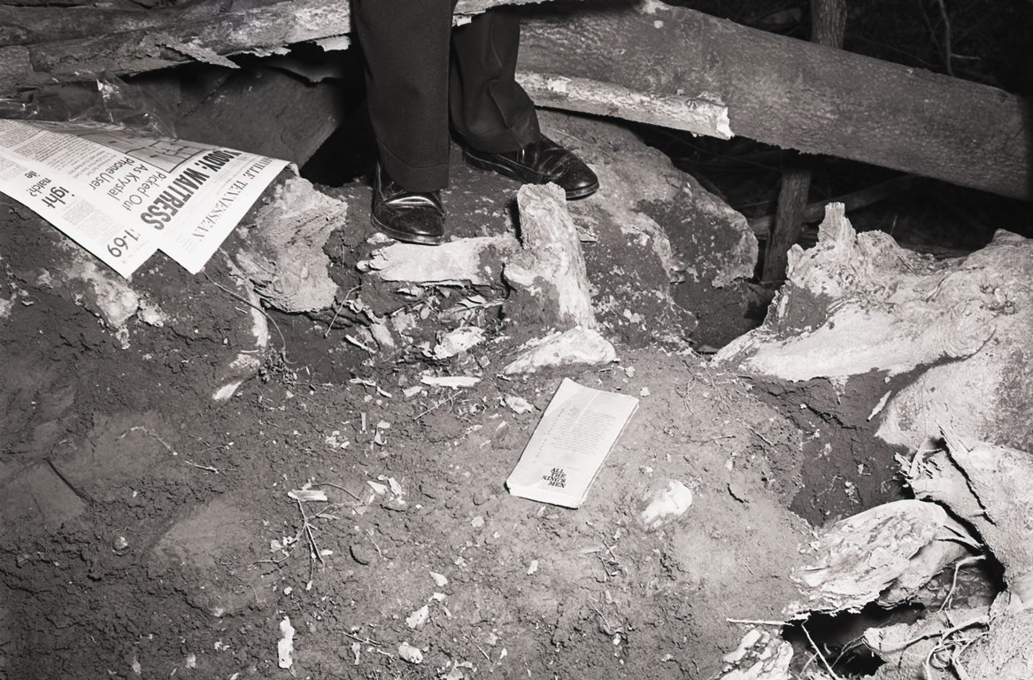A pair of shoes attached to a legs stand over a messy scene with a The Tennessean newspaper.