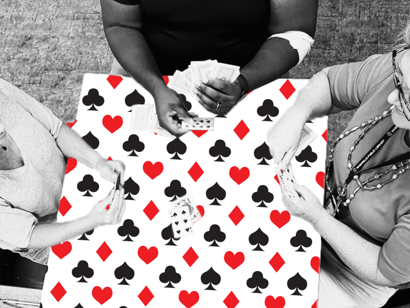 Three people playing cards on a table decorated with card suits.
