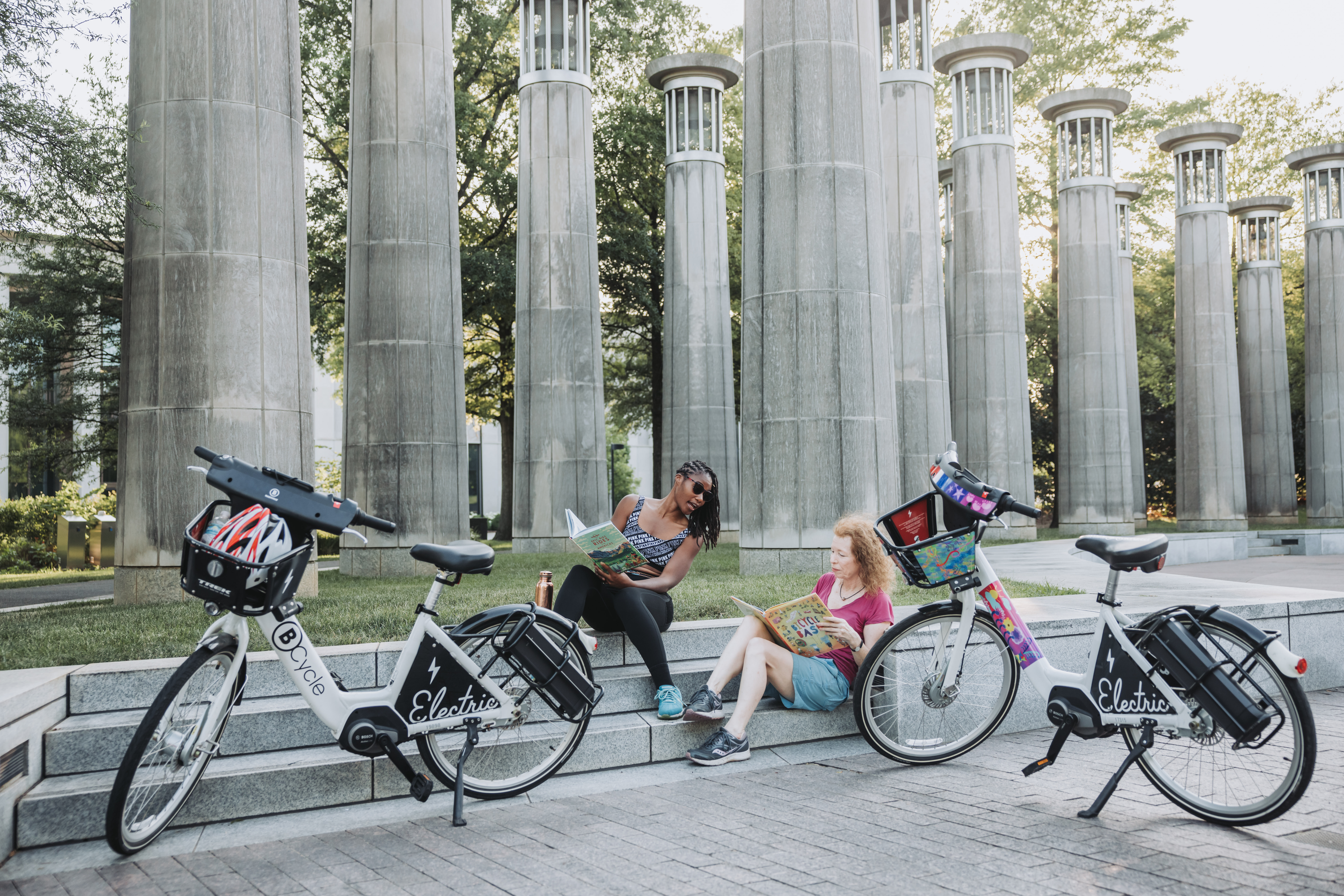 Two women relaxing on steps at Bicentennial Mall next to bicycles.