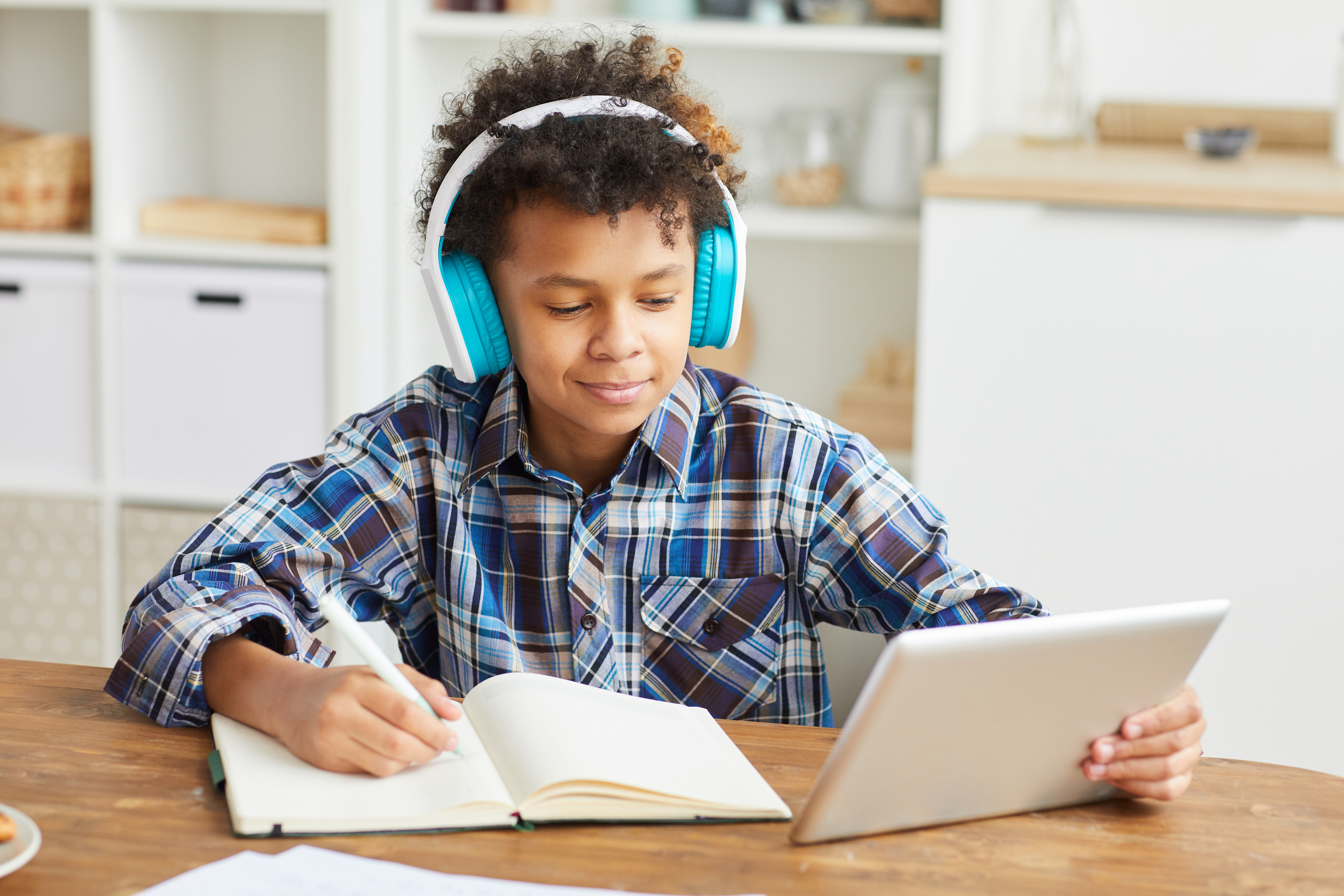 Boy reading with headphones and a tablet.