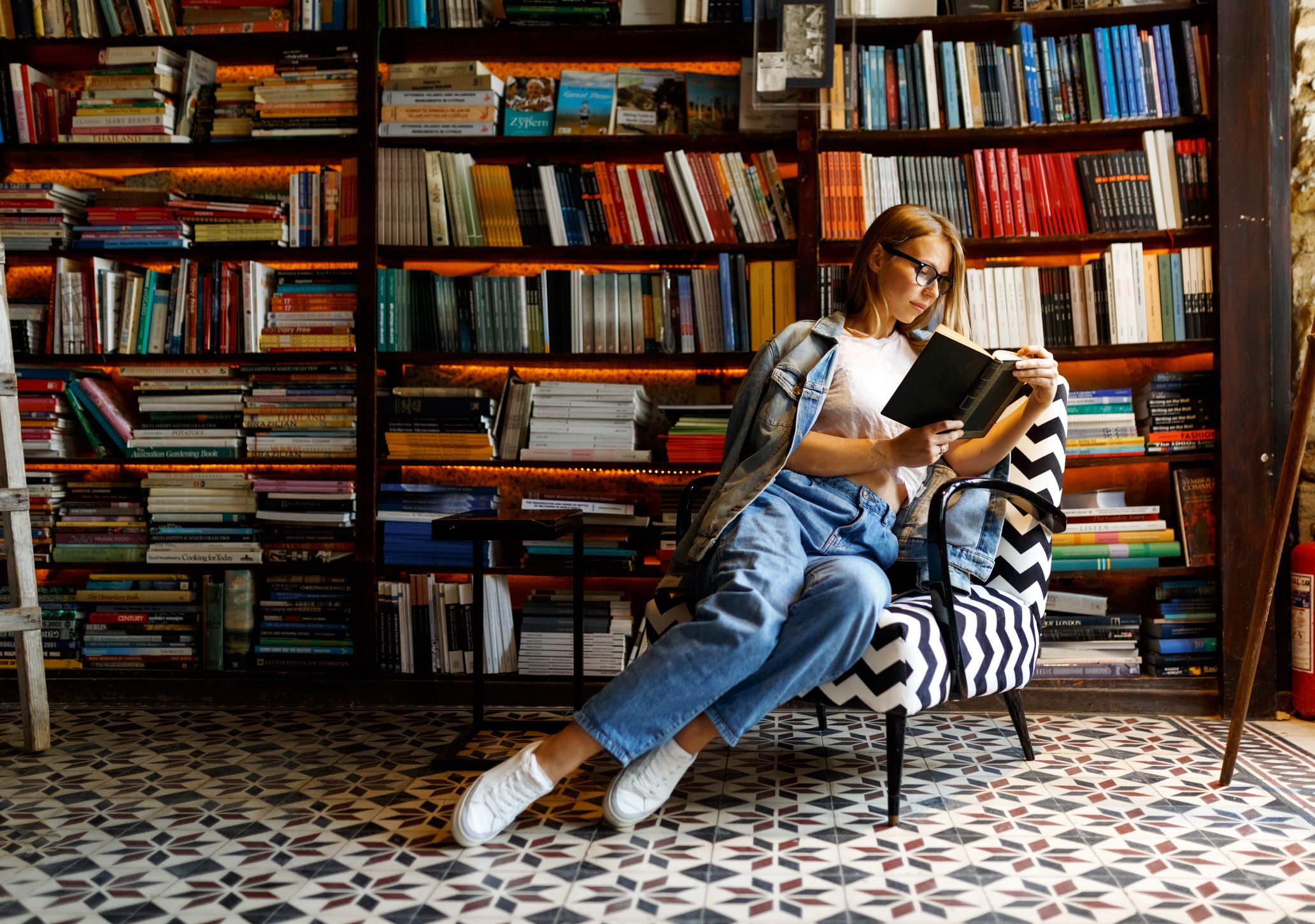 Girl reading in front of bookshelf.