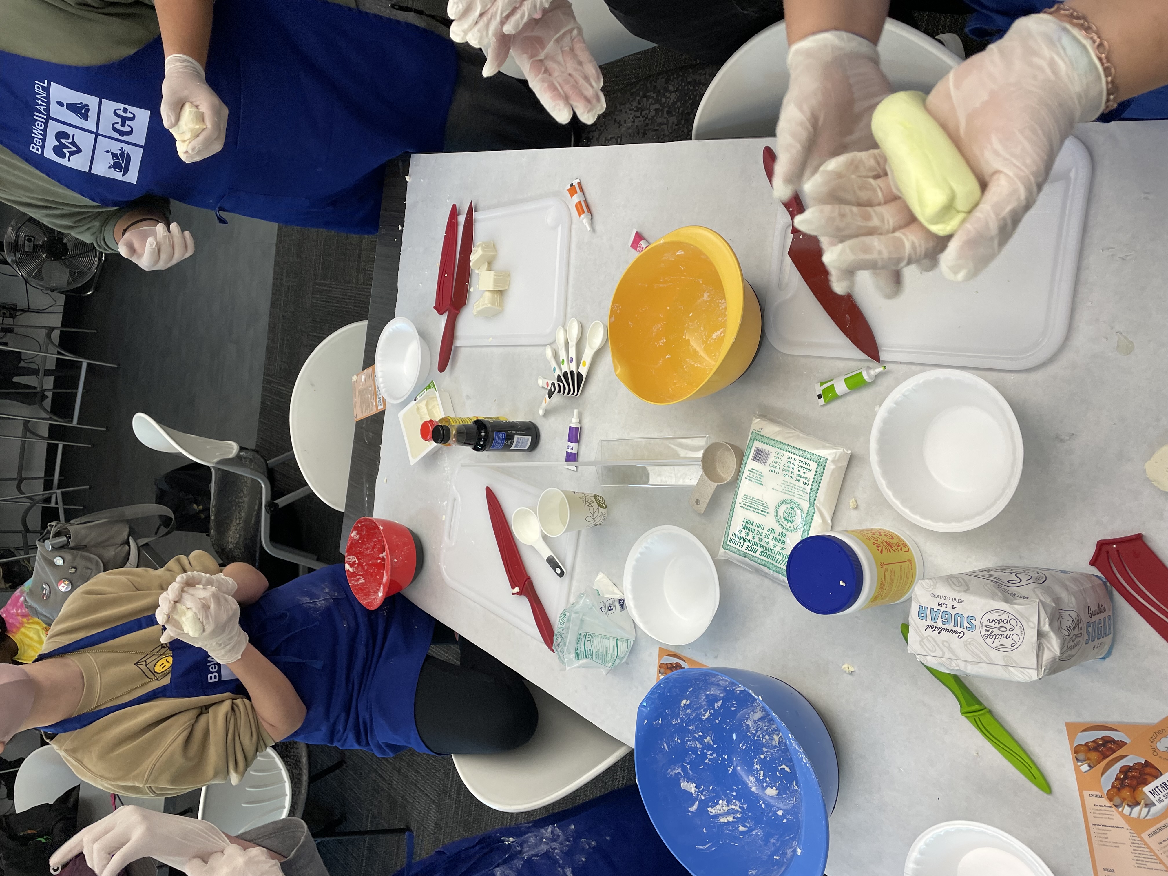 People doing a crafting or baking project using measuring spoons and food coloring.