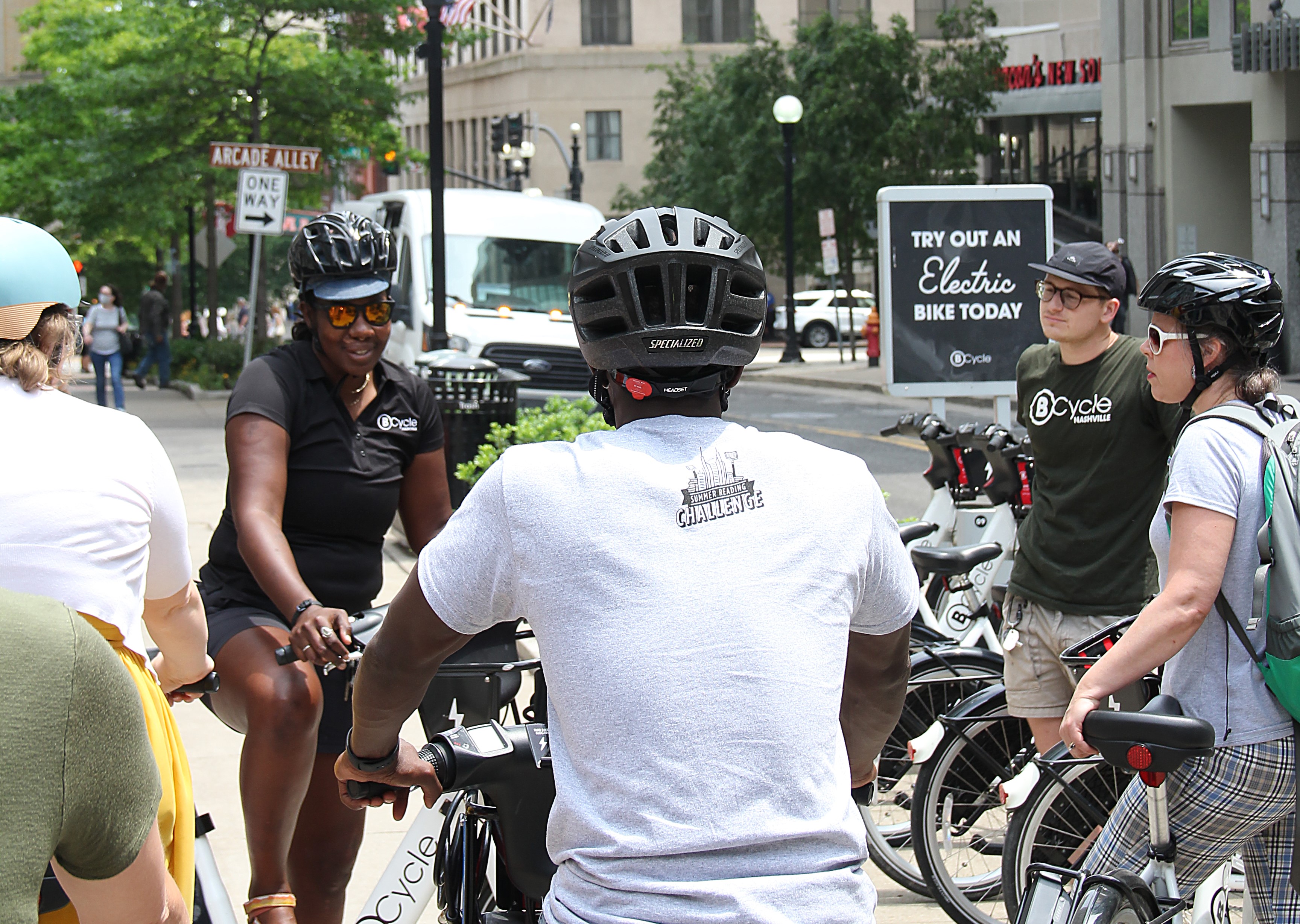 Small group of people with bike helmets on, standing with bikes.