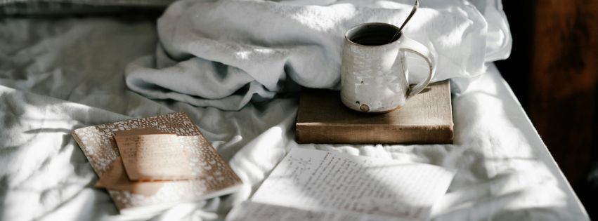 white blanket with books and cup of coffee set