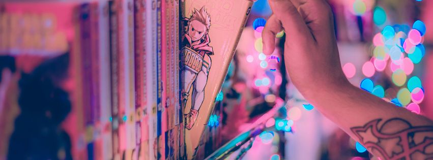 hand pulling a volume of manga on shelf