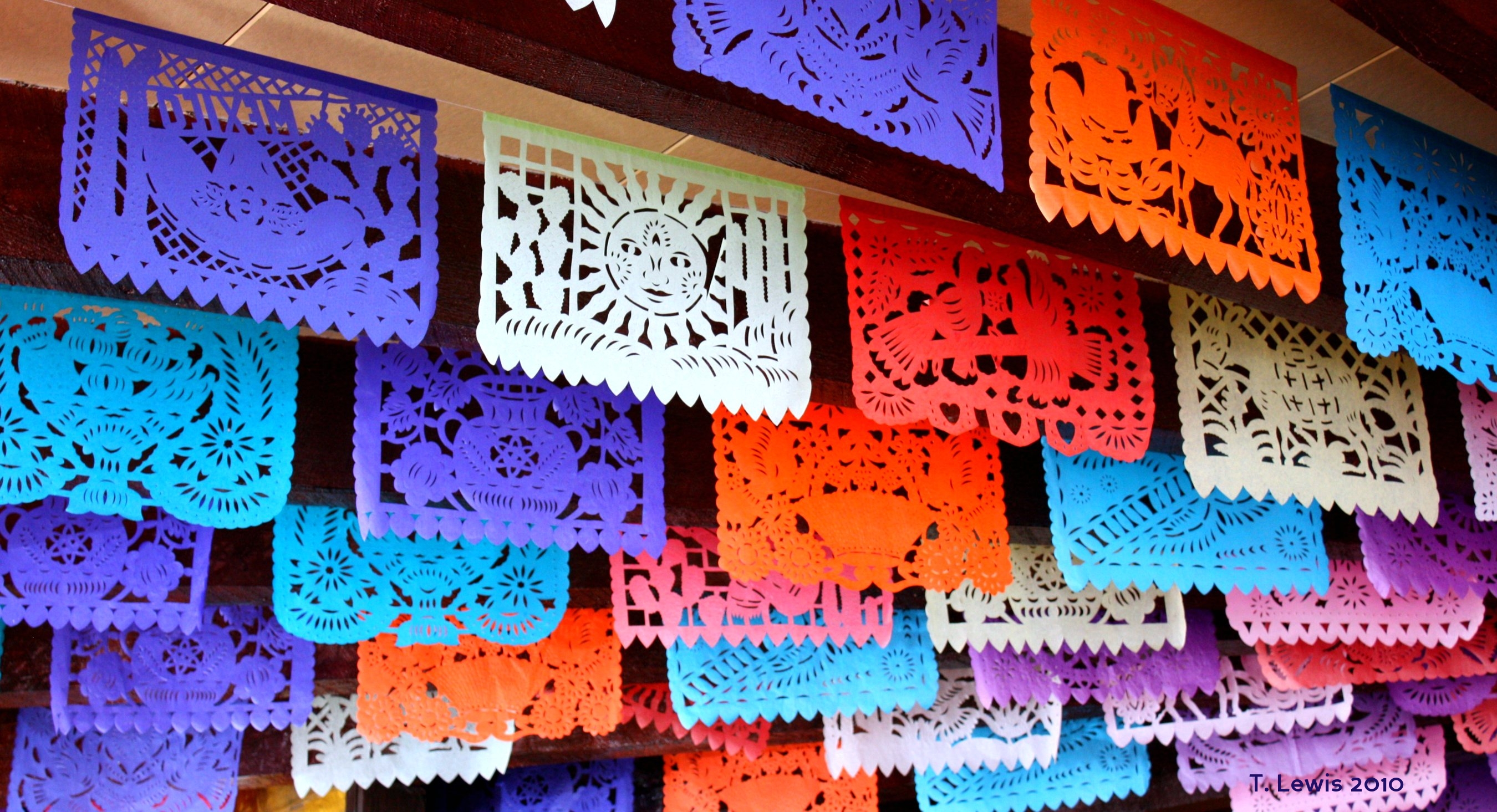 Red, purple, white, and orange prayer flags hang from a ceiling