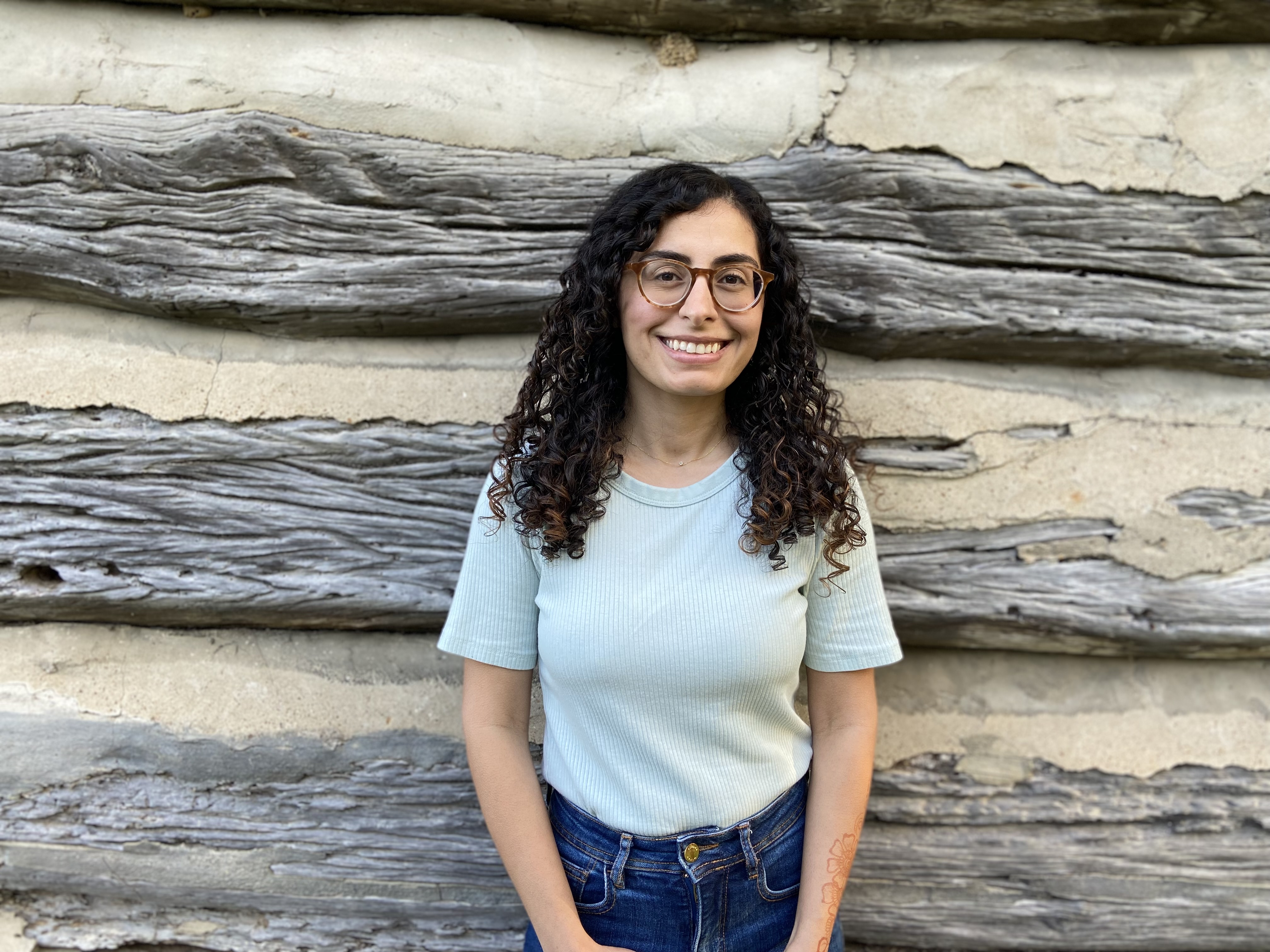 woman with long brown hair, glasses, and a blue shirt
