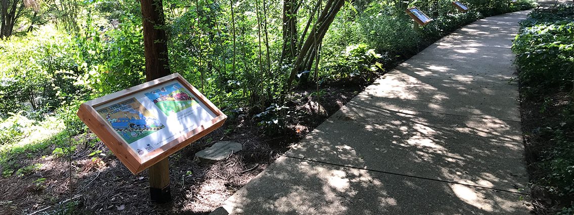 Wooden signs along a paved walking trail