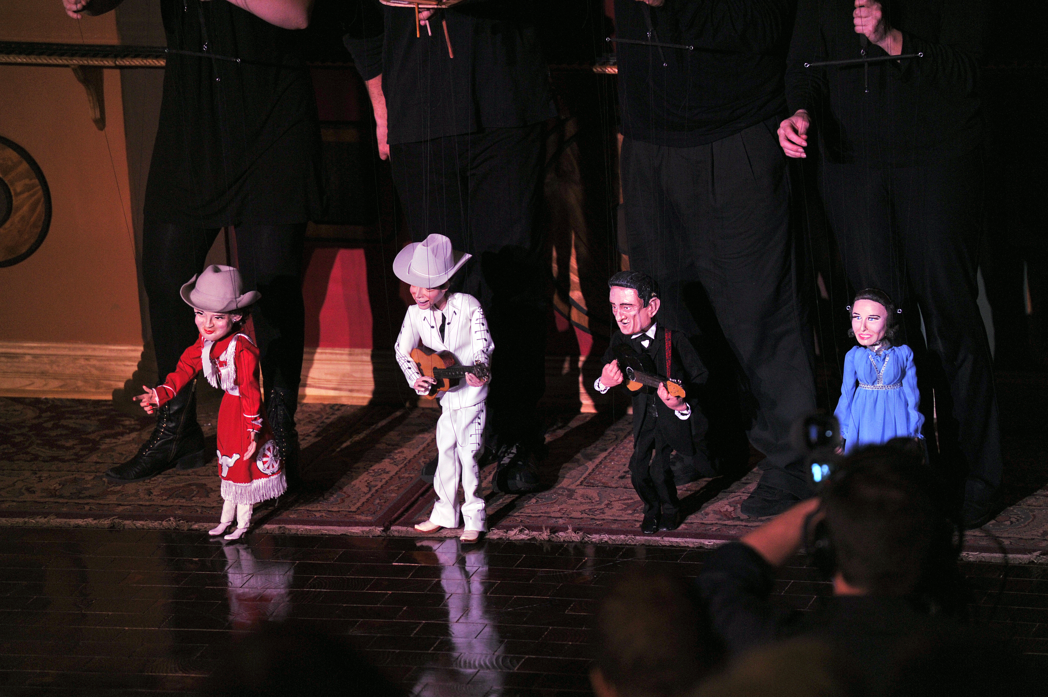 Puppeteers in all black perform 4 musician marionettes