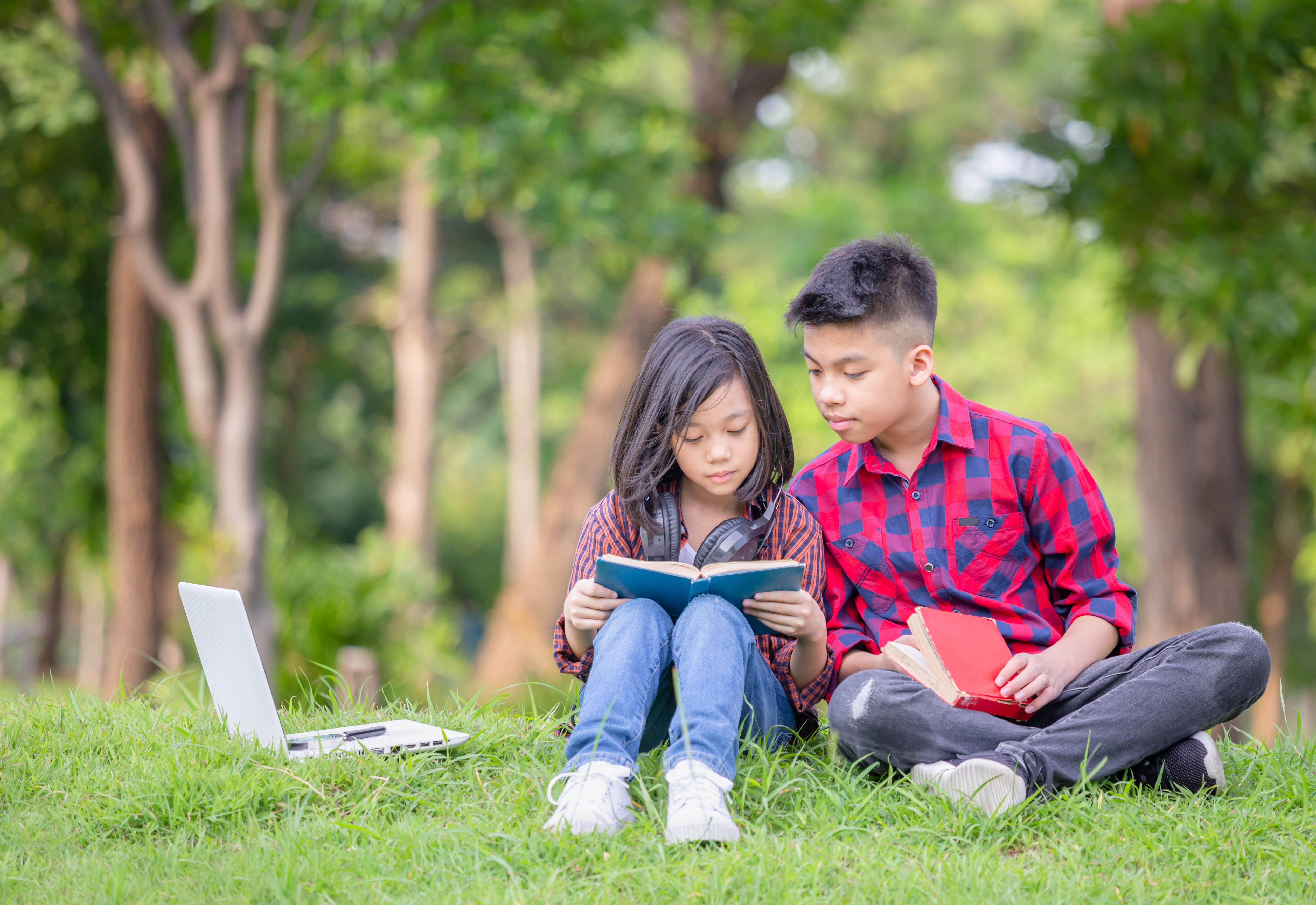 Children reading books in a wooded area.