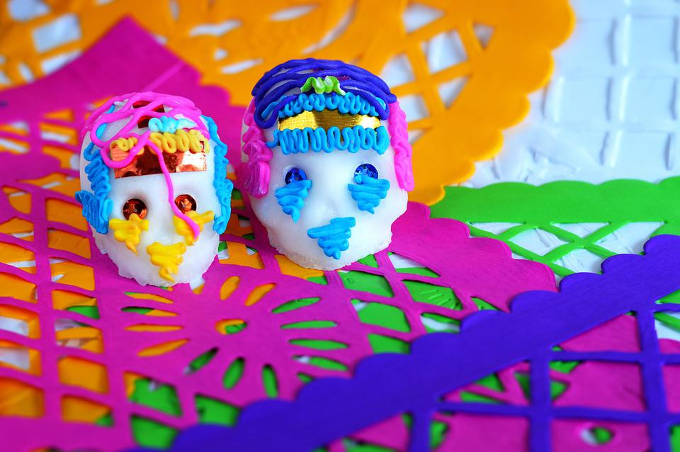 Pink, purple, orange, and green prayer flags with two sugar skulls decorated in icing.