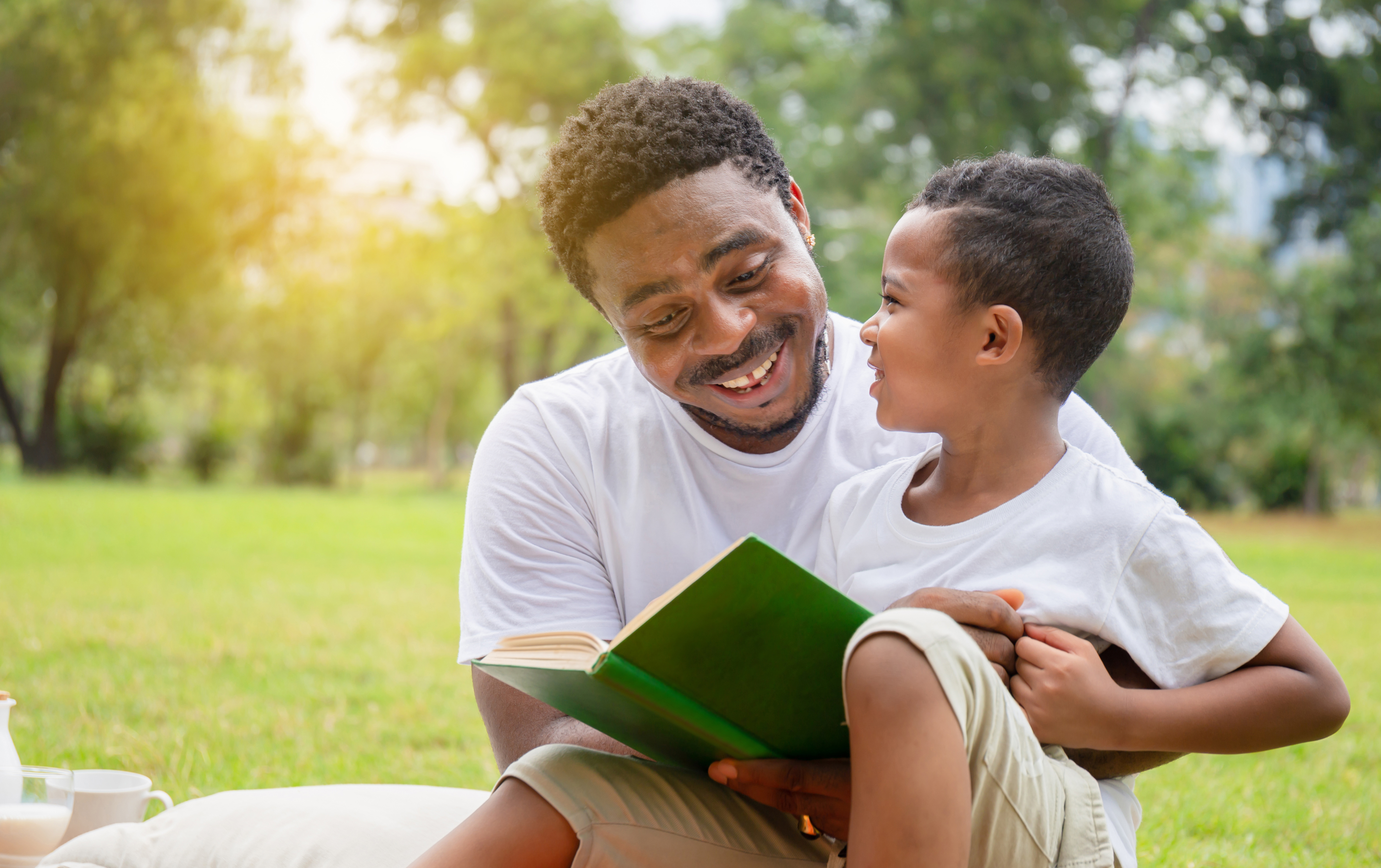 father and son reading outdoors