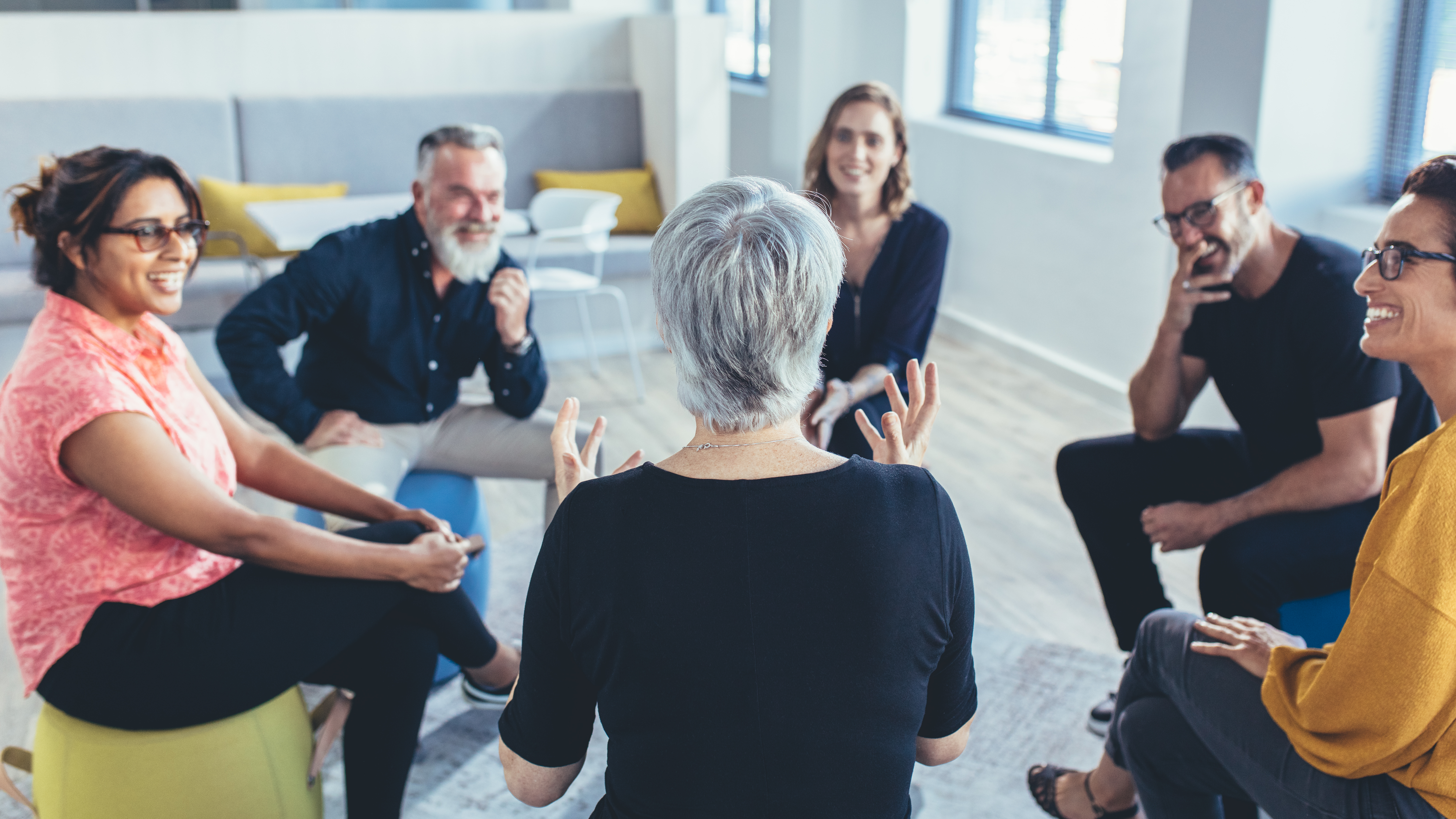 Group of adults sitting in a circle, talking.