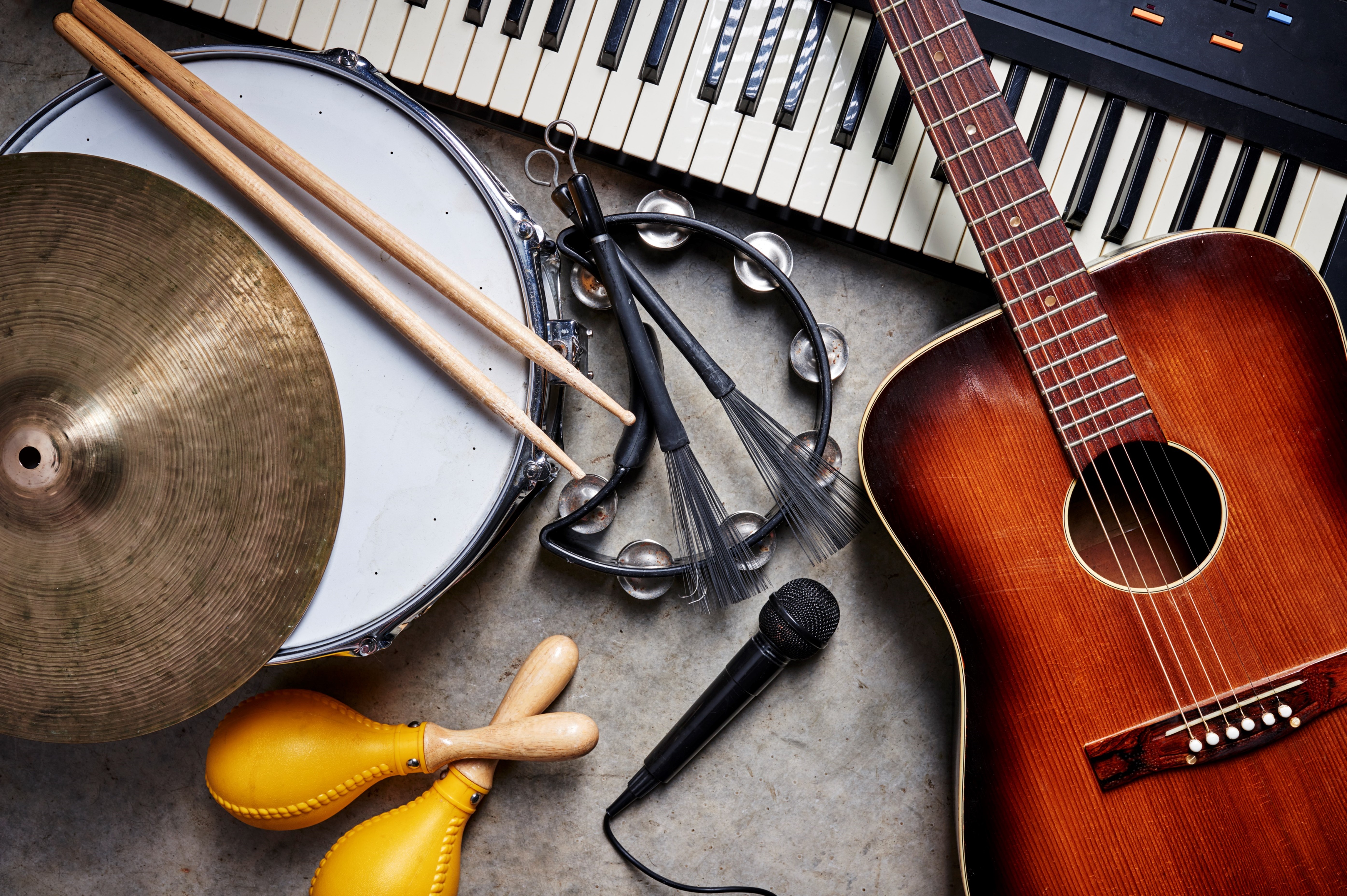 Instruments laying on a table, including guitar, keyboard, and cymbals.