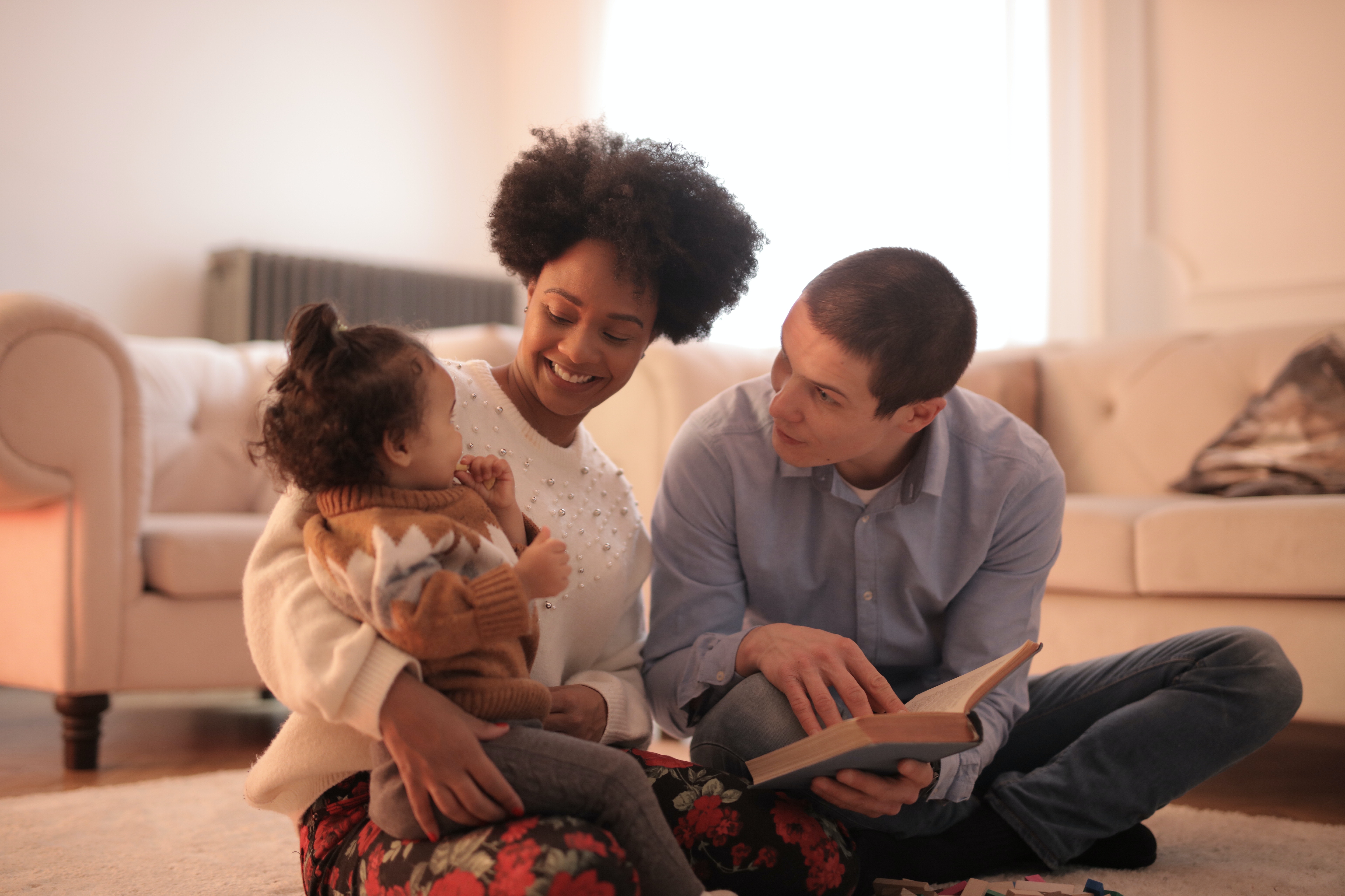 Family sitting on the floor reading a book