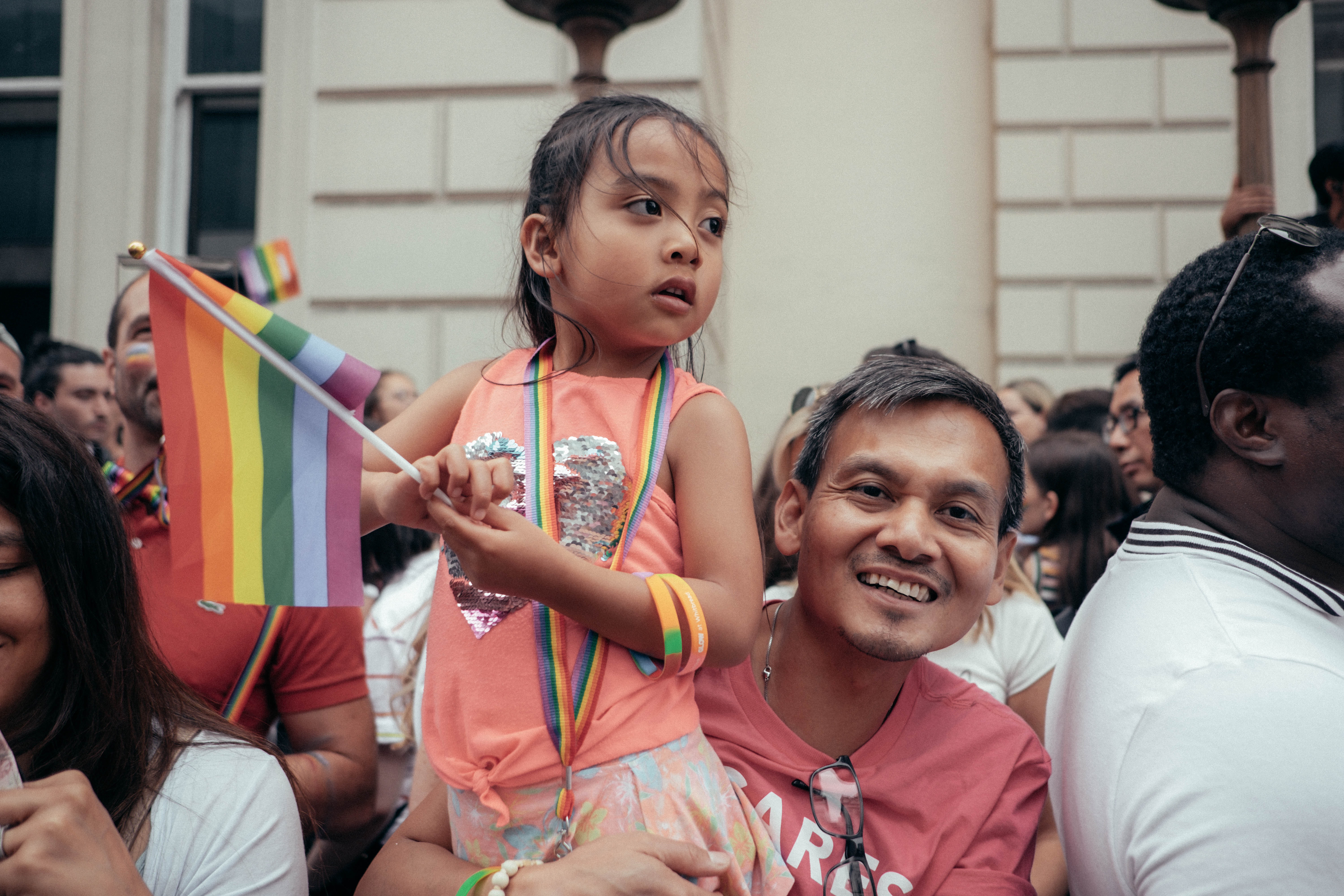 Man holds young girl who holds a rainbow flag