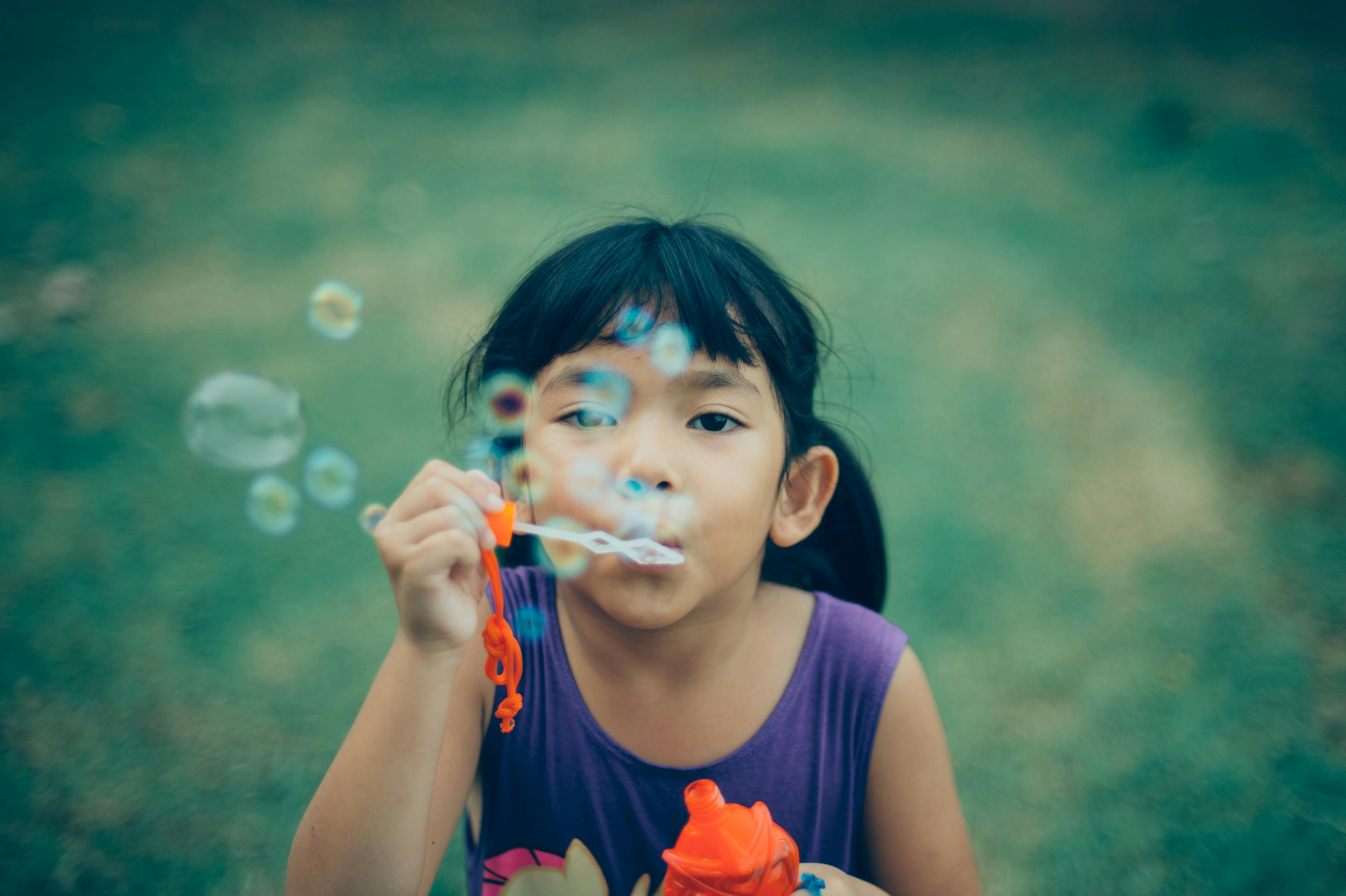Young girl with dark hair blows bubbles in the sky