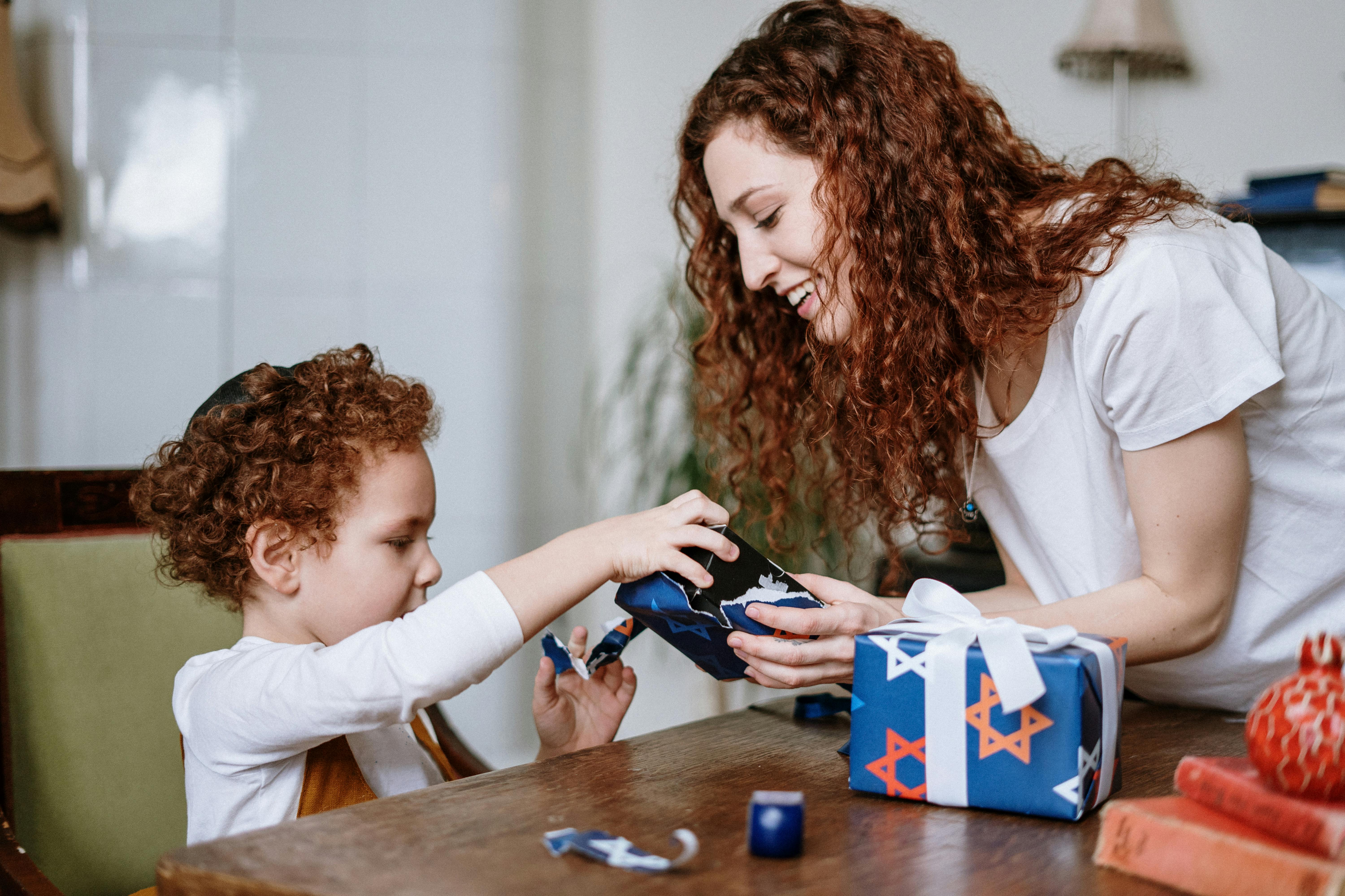 Woman with red curly hair opens a gift with a small child